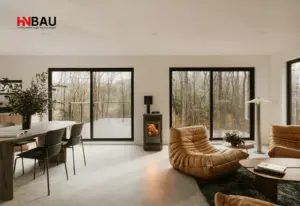 Modernes Wohnzimmer mit großen energieeffizienten bodentiefen Fenstern und Schiebetüren, die viel Tageslicht hineinlassen und für hohen Wärmeschutz sorgen – Beispiel für moderne Fensterlösungen von HN-Bau.