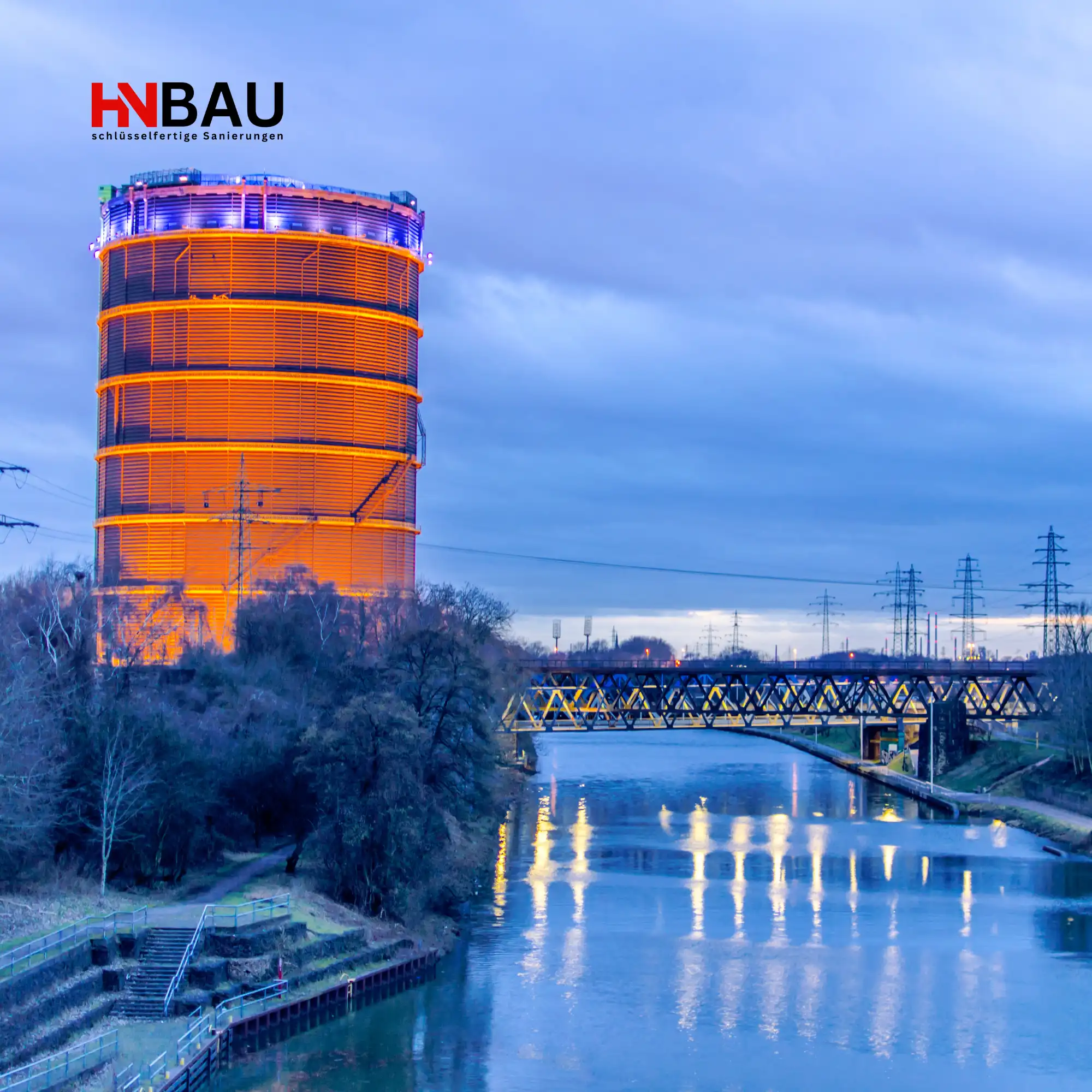 Gasometer Oberhausen bei Abendbeleuchtung mit Blick auf Kanal und Brücke – Symbol für die Region, in der HN-Bau Sanierungsarbeiten anbietet.