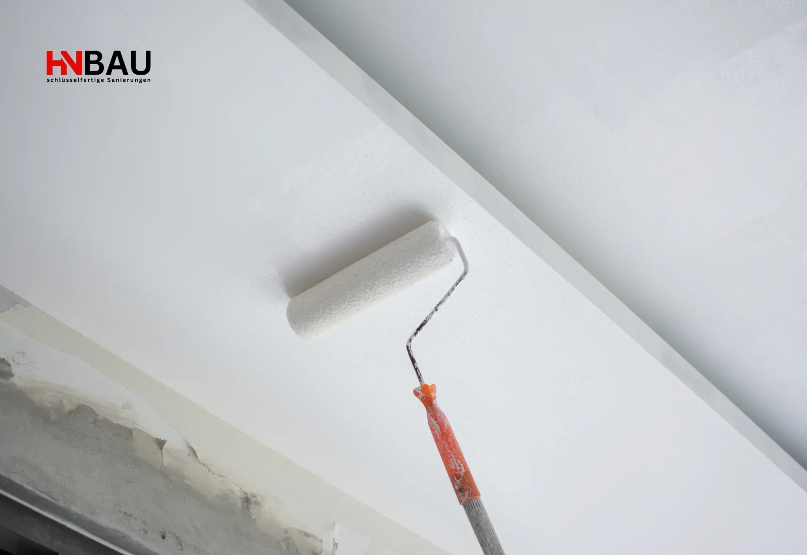 Farbrolle auf Verlängerungsstab trägt frischen Anstrich auf eine Zimmerdecke auf; Renovierungsarbeiten im Innenbereich.