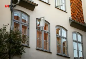 Altbau-Fassade eines Mehrfamilienhauses aus den 1950er–1970er Jahren mit klassischen Holzfenstern und Ziegeldach – Symbolbild für typische Bauweise und energetische Schwachstellen älterer Bestandsgebäude.