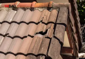 Beschädigtes Ziegeldach mit gerissenen und verschobenen Dachziegeln am Dachrand – Symbolbild für Sanierungsbedarf, Undichtigkeiten und die Entscheidung zwischen Neueindeckung und kompletter Dachsanierung.