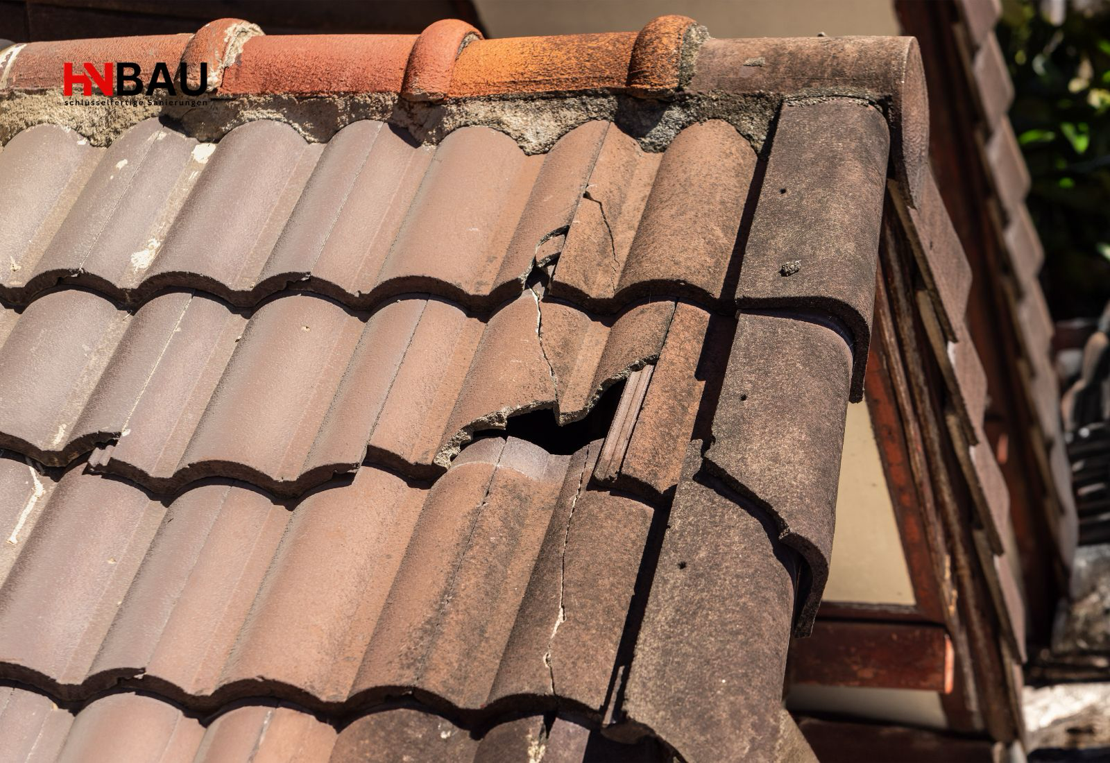 Beschädigtes Ziegeldach mit gerissenen und verschobenen Dachziegeln am Dachrand – Symbolbild für Sanierungsbedarf, Undichtigkeiten und die Entscheidung zwischen Neueindeckung und kompletter Dachsanierung.