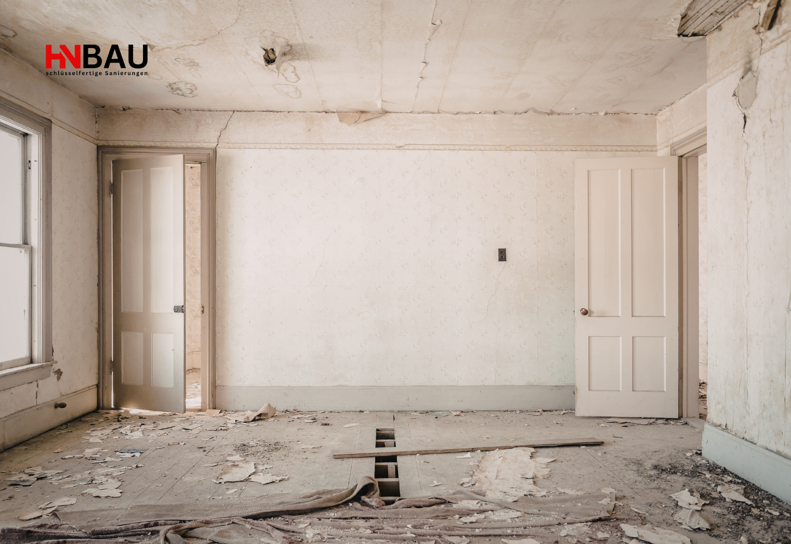 Altbauzimmer im unsanierten Zustand mit beschädigtem Boden, Rissen in der Decke und geöffneten Türen – typisches Beispiel vor einer Komplettsanierung